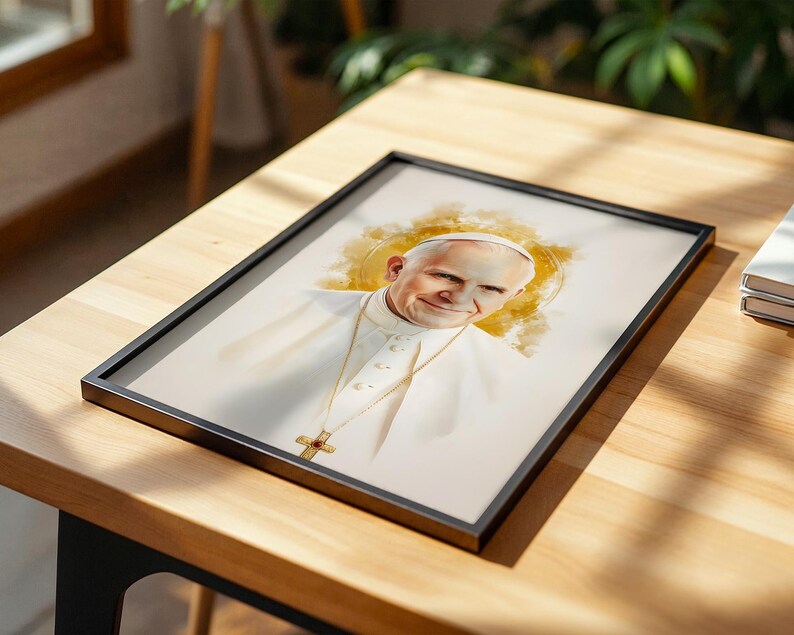 May include: A framed portrait print featuring a watercolour-style illustration of Pope John Paul II wearing a white cassock and a gold crucifix necklace, set against a soft, golden-yellow circular halo effect on a light, neutral background.