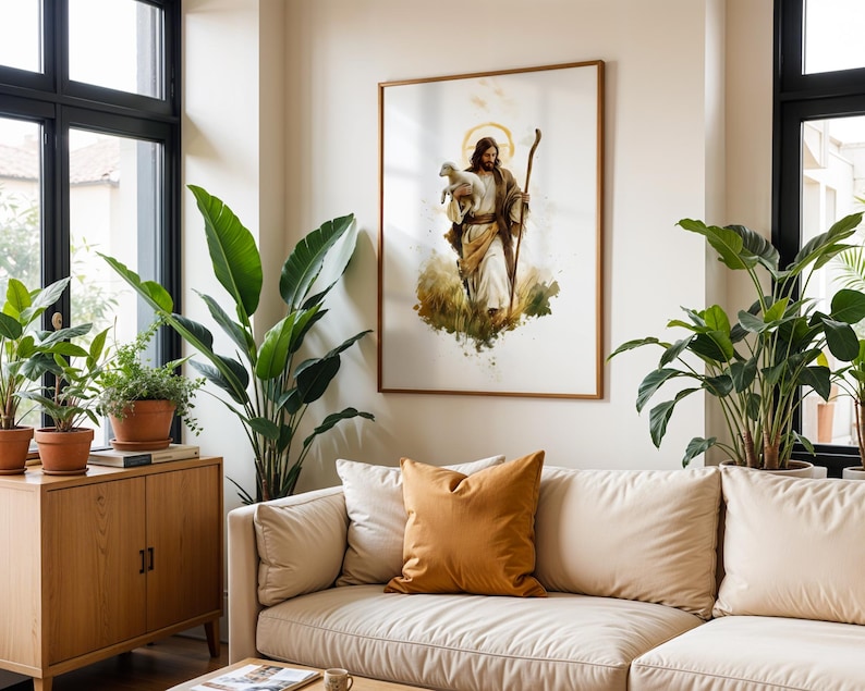 May include: A framed wall art print featuring a watercolour-style illustration of a figure with long brown hair and a beard, wearing robes, holding a small white lamb in one arm and a wooden staff in the other, set against a white background.