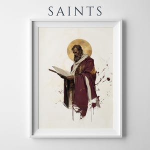 May include: A framed wall art print titled SAINTS featuring a bearded figure in a deep maroon robe and white shawl reading an open book. A golden circular halo sits behind the head, with abstract paint splatters in dark red and gold tones.