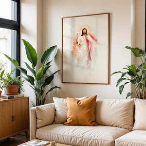 May include: A framed wall art print depicting a figure with long brown hair and a beard, wearing a white robe with red accents, surrounded by a golden light halo. The artwork is displayed on a plain wall above a beige sofa with a mustard pillow.