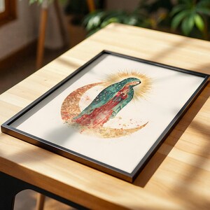 Puede incluir: Una l&aacute;mina enmarcada con una ilustraci&oacute;n en acuarela de la Virgen de Guadalupe sobre una luna creciente. Viste un manto color verde azulado con estrellas doradas sobre un vestido rojo, con un halo dorado radiante tras su cabeza.