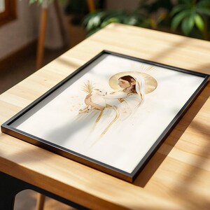 Pode incluir: Uma impress&atilde;o art&iacute;stica emoldurada apresentando uma ilustra&ccedil;&atilde;o estilizada de uma figura com um halo dourado, vestindo mantos brancos e segurando um pequeno coelho branco. A obra usa tons suaves de dourado e branco com linhas delicadas.