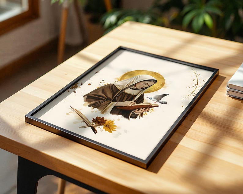 May include: A framed print featuring an illustration of a figure in a brown habit and white head covering writing in a book. A golden halo surrounds the head, with a small bird, a quill, and yellow and brown flowers depicted on a cream background.
