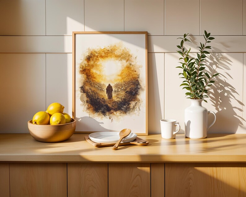 K&ouml;nnte beinhalten: Ein gerahmter Druck im Aquarellstil, der eine einsame Gestalt zeigt, die auf eine helle goldene Sonne zugeht, platziert auf einer Holztheke neben einer Schale mit gelben Zitronen, einem wei&szlig;en Teller mit Holzl&ouml;ffel, einer wei&szlig;en Tasse und einer wei&szlig;en Vase.