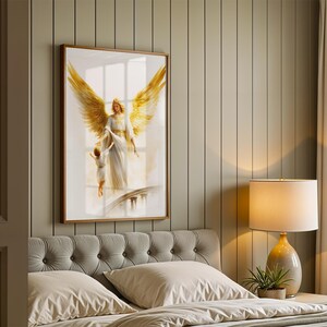 May include: A framed wall art print featuring a golden-winged angel in a white robe holding the hand of a small child. The artwork is displayed in a wooden frame on a vertical paneled wall above a tufted headboard and a bedside lamp.