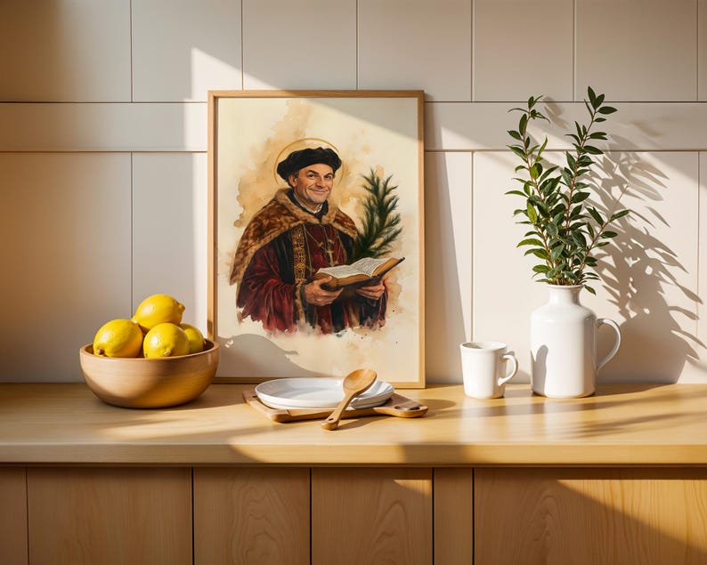 May include: A framed watercolor-style print depicting a historical figure in a dark cap and fur-trimmed robe holding an open book and a palm frond. The artwork is displayed on a wooden counter alongside a bowl of yellow lemons and a white vase.