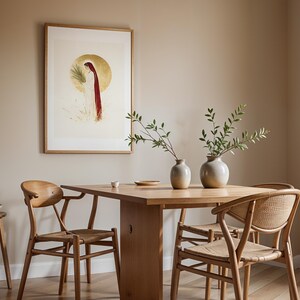 Puede incluir: Una l&aacute;mina de pared enmarcada que representa una figura con t&uacute;nica blanca y capa roja sobre un fondo circular dorado, situada sobre una mesa de comedor de madera con dos jarrones de cer&aacute;mica con ramas verdes y tres sillas de madera.