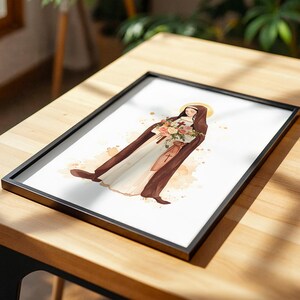 Peut inclure: Une impression d'art encadr&eacute;e repr&eacute;sentant une illustration &agrave; l'aquarelle d'une religieuse en habit marron et voile blanc, tenant un bouquet de roses roses, blanches et orange. Une petite croix est visible sur l'habit et une aur&eacute;ole dor&eacute;e brille.