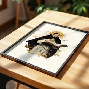 May include: A framed print featuring an illustration of a figure in a black and white religious habit, holding an open book. A golden sunburst halo radiates from behind the head, with ink-like brown splatters surrounding the central figure.