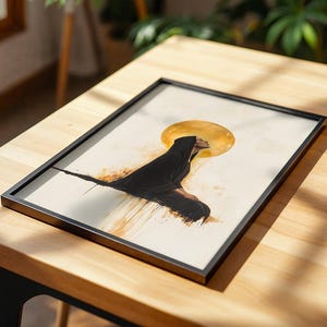 May include: A framed rectangular print featuring a side profile illustration of a figure wearing a black hooded cloak. Behind the figure is a large, circular golden sun or halo. The artwork includes abstract golden paint drips on a cream background.