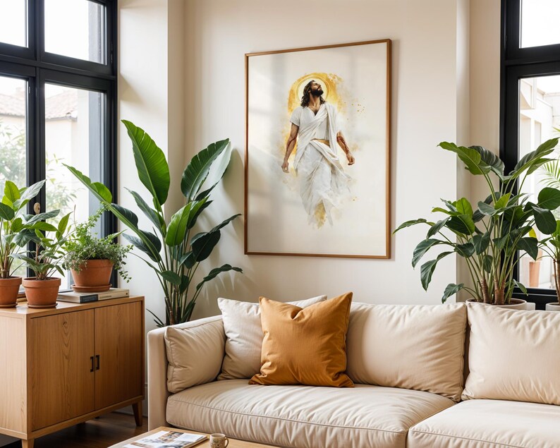 May include: A framed wall art print featuring a figure with long hair and a beard, dressed in flowing white robes, depicted in a watercolor style with a golden circular halo behind the head, set against a light cream-colored background.