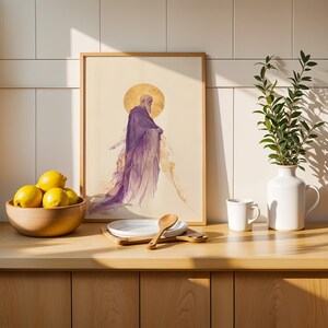 May include: A framed wall art print featuring a bearded figure in a flowing purple robe with a golden halo, displayed next to a wooden bowl of yellow lemons, a white plate with a wooden spoon, a white mug, and a white vase with green leaves.