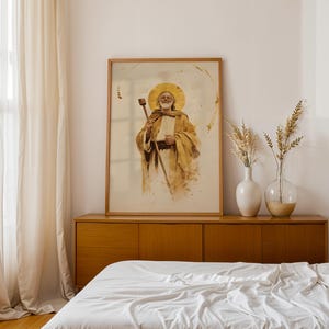 Puede incluir: Una l&aacute;mina de arte mural vertical enmarcada que presenta una ilustraci&oacute;n estilo acuarela de una figura barbuda con un halo dorado, vistiendo t&uacute;nicas color canela y sosteniendo un bast&oacute;n de madera. La obra usa tonos dorados, beige y marrones.