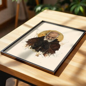 Puede incluir: Una l&aacute;mina enmarcada con una ilustraci&oacute;n estilo acuarela de un hombre barbudo con halo, que viste una t&uacute;nica marr&oacute;n con capucha y sostiene una peque&ntilde;a cruz. La obra utiliza tonos marrones, crema y dorados en un marco negro fino.