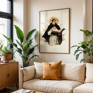 May include: A framed wall art print featuring a religious figure in a black and white habit, holding an open book with a golden sunburst halo behind the head. The illustration uses ink-wash style accents in shades of brown and black on a cream background.