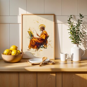 Puede incluir: Una l&aacute;mina enmarcada con una ilustraci&oacute;n en acuarela de una figura barbuda con t&uacute;nica naranja pintando un retrato en un caballete. La obra se exhibe sobre una encimera de madera junto a un cuenco de limones amarillos, un plato blanco y un jarr&oacute;n.