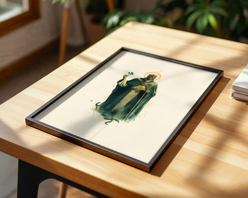 May include: A framed art print featuring a watercolor-style illustration of a bearded figure wearing a dark green robe and a golden halo, holding a small green shamrock in one hand and a circular golden object in the other against a cream background.