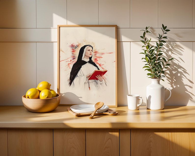 K&ouml;nnte beinhalten: Ein gerahmter Kunstdruck mit einer Aquarell-Illustration einer Nonne in schwarz-wei&szlig;em Habit, die ein rotes Buch h&auml;lt, vor einem leuchtend roten und orangefarbenen Sonnenstrahlen-Hintergrund, pr&auml;sentiert in einem hellen Holzrahmen auf einer K&uuml;chentheke.