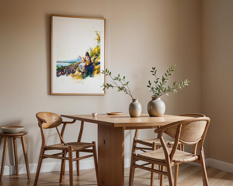 May include: A framed watercolour-style print depicting a figure in robes addressing a large crowd near a body of water, mounted on a beige wall above a wooden dining table with two ceramic vases, four wooden chairs, and a small wooden stool.