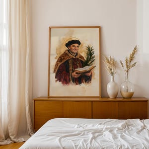 May include: A framed watercolor portrait of a man wearing a dark cap and a maroon robe with gold trim, holding an open book and a green palm frond. The figure has a golden halo around his head, set against a light beige, textured background.