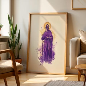 May include: A framed vertical wall art print featuring a bearded figure in a purple robe holding a staff. The figure has a golden halo behind their head, set against a cream background with purple watercolor-style splashes at the base.