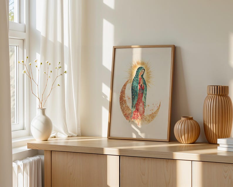 Puede incluir: Una l&aacute;mina de arte mural enmarcada con una ilustraci&oacute;n en acuarela de la Virgen de Guadalupe sobre una luna creciente con un halo dorado detr&aacute;s de la cabeza, en tonos verde azulado, rojo y dorado sobre un fondo claro.
