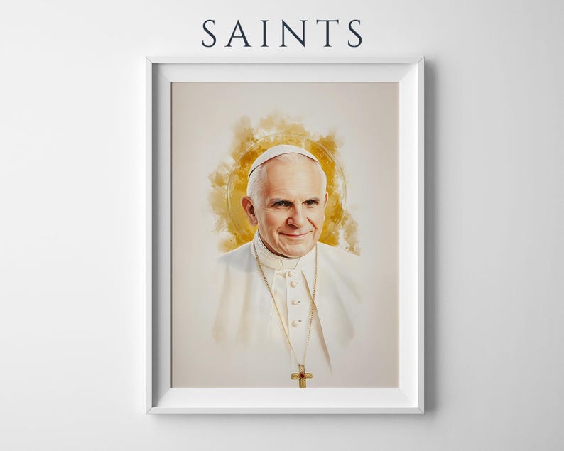 May include: A framed portrait print featuring the word SAINTS at the top. The artwork depicts a watercolour-style illustration of Pope John Paul II wearing a white cassock and a gold cross necklace, set against a soft, golden circular halo.