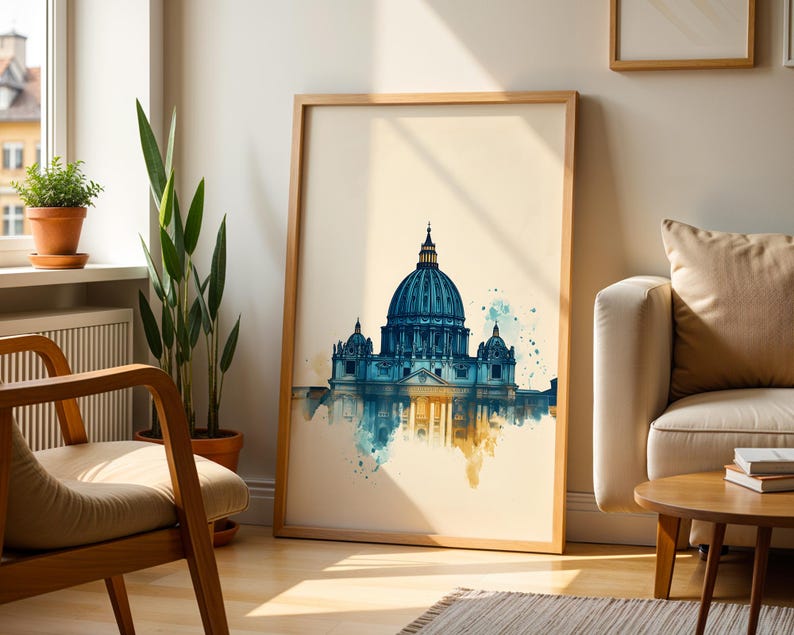 May include: A framed wall art print featuring a watercolour illustration of a large domed cathedral. The artwork displays deep blue and teal tones for the architecture, with soft yellow and orange paint splatters at the base on a cream background.