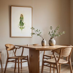 Op de afbeelding: Een ingelijste verticale wandkunstprint met een figuur in een groene jurk die een zwaard vasthoudt, boven een houten eettafel met twee keramische vazen met groene bladeren en drie houten stoelen met gevlochten zittingen.