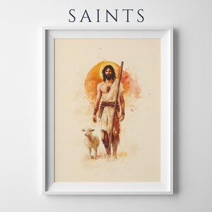 Peut inclure: Une impression d'art encadr&eacute;e intitul&eacute;e SAINTS repr&eacute;sentant une illustration &agrave; l'aquarelle d'une figure barbue avec une aur&eacute;ole, v&ecirc;tue d'une robe blanche et tenant un b&acirc;ton en bois, accompagn&eacute;e d'un petit agneau blanc sur fond orange et cr&egrave;me.