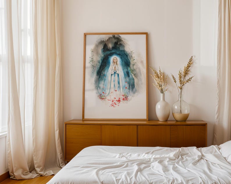 Puede incluir: Una l&aacute;mina de acuarela enmarcada que representa una figura con t&uacute;nica blanca y azul con las manos juntas en oraci&oacute;n, rodeada por un fondo de gruta azul oscuro y verde azulado con p&eacute;talos de rosa rojos esparcidos, en un marco de madera clara.