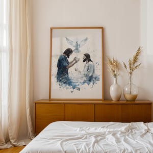 Peut inclure: Une impression d'art encadr&eacute;e de style aquarelle repr&eacute;sentant une sc&egrave;ne de bapt&ecirc;me avec deux personnages dans l'eau bleue, l'un les mains lev&eacute;es et l'autre lui faisant face, tandis qu'une colombe blanche descend sur fond blanc.