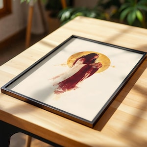 以下が含まれることがあります： 長い黒髪の人物が白と濃い赤のローブを纏った姿を描いた、額装された長方形のアートプリント。人物はクリーム色の紙の上に描かれ、背景には大きな円形の黄金色の太陽のようなモチーフが中央に配置されている。
