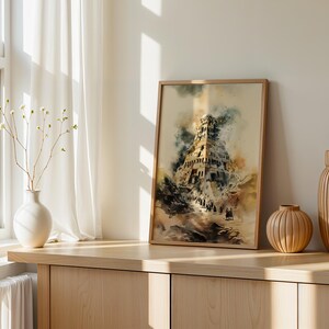 May include: A framed watercolor-style print depicting a multi-tiered ancient tower structure with dark, smoky clouds and figures walking along a path, rendered in muted tones of brown, blue, and cream, displayed in a light wood frame.