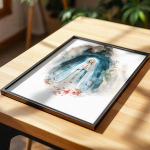 Peut inclure: Une impression aquarelle encadr&eacute;e repr&eacute;sentant une silhouette v&ecirc;tue d'une robe blanche et bleue, les mains jointes en pri&egrave;re, entour&eacute;e d'un fond bleu sombre &eacute;voquant une grotte avec des p&eacute;tales de roses rouges &agrave; la base, sous cadre noir.