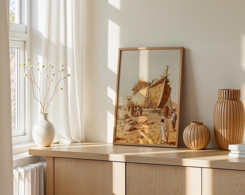 May include: A framed wall art print depicting a large wooden ship under construction in a desert landscape with figures in robes standing nearby. The artwork features warm beige and brown tones, showcasing the hull and scaffolding of the vessel.