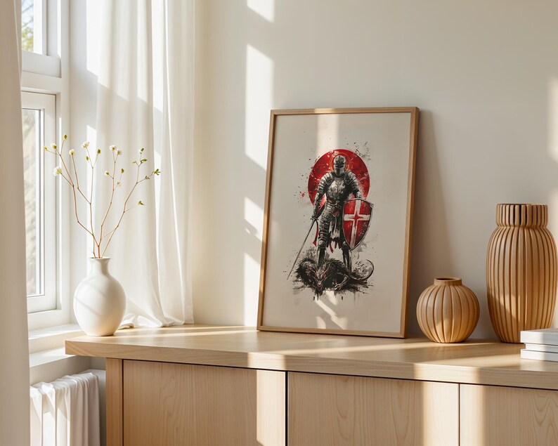 May include: A framed wall art print featuring a knight in full armour holding a sword and a shield with a red cross, standing over a dark creature. The illustration uses a red circular background with ink splatter effects on a light background.
