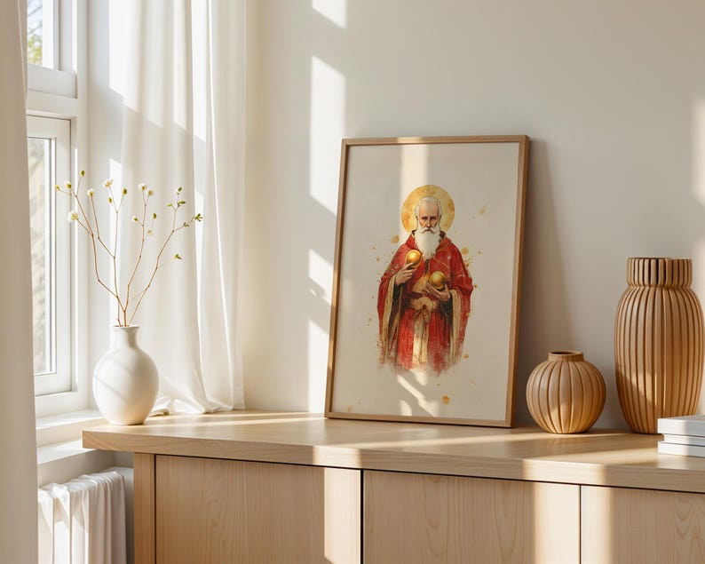 May include: A framed vertical print featuring a watercolor illustration of a bearded figure in red robes with a golden halo, holding two golden spheres. The artwork is displayed in a light wood frame, positioned on a wooden surface with vases.