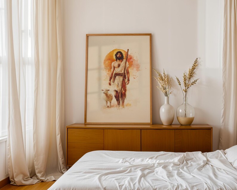 May include: A framed vertical wall art print featuring a watercolor illustration of a bearded figure in light-colored robes holding a wooden staff, walking alongside a small white lamb against a large, circular, warm orange sun background.