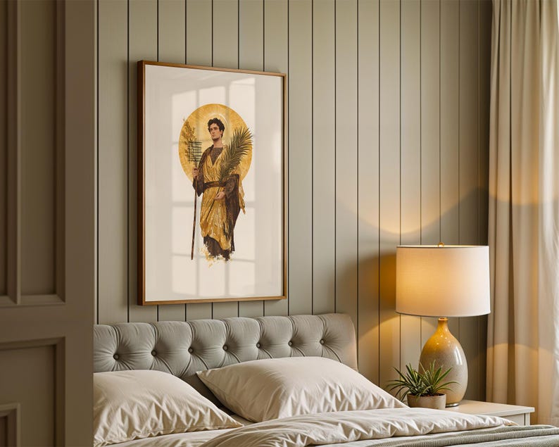 Op de afbeelding: Een ingelijste kunstprint met een figuur in gouden gewaden voor een grote cirkelvormige halo. De figuur houdt een hoge staf en een palmblad vast. Het kunstwerk is ingelijst in een houten lijst aan een verticaal beklede wand boven een gecapitonneerd hoofdbord.