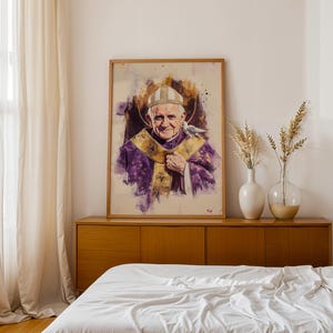 Peut inclure: Un portrait encadr&eacute; style aquarelle du Pape Jean-Paul II portant une mitre blanche et des v&ecirc;tements liturgiques violets avec des bordures dor&eacute;es. Une petite colombe blanche repose sur son &eacute;paule, sur un fond de taches de peinture violettes et dor&eacute;es.
