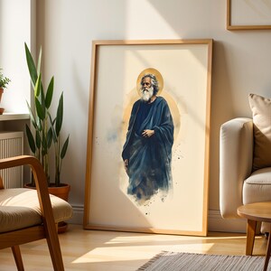 May include: A framed wall art print featuring a watercolor-style illustration of a bearded figure with long gray hair, wearing a dark blue robe. The figure is centered against a soft cream background with a circular golden halo behind the head.