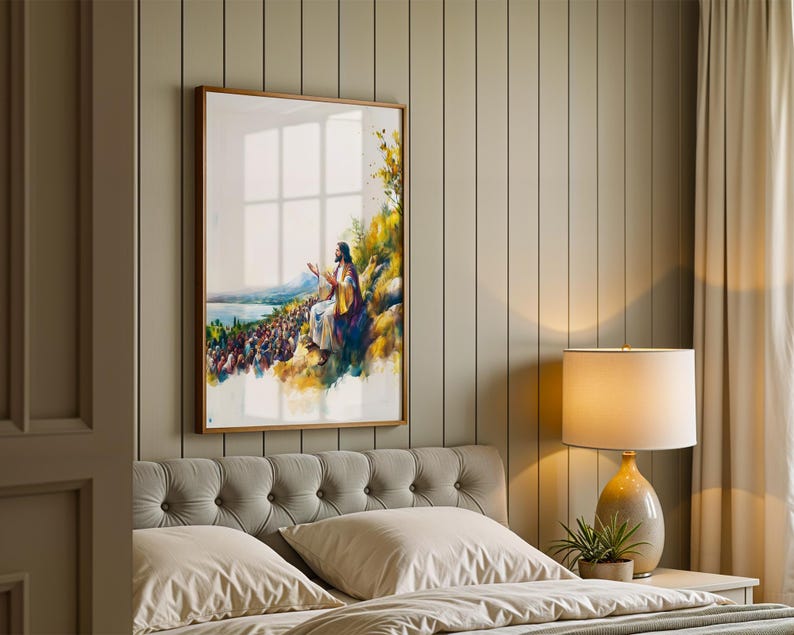 May include: A framed vertical wall art print featuring a watercolour-style illustration of a figure in robes sitting on a hillside, gesturing towards a large crowd gathered below near a body of water, with yellow and green foliage accents.