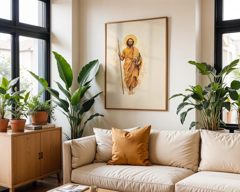Op de afbeelding: Een ingelijste kunstdruk met een bebaarde figuur in een gouden gewaad die een lange staf en een boekrol vasthoudt, met een cirkelvormige halo achter het hoofd. Het kunstwerk hangt aan een lichte muur boven een beige bank met een mosterdkleurig kussen.