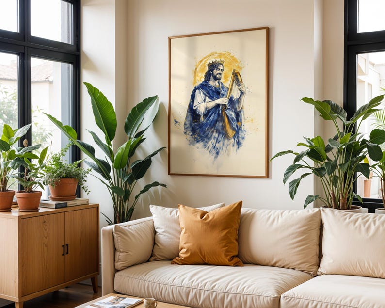 K&ouml;nnte beinhalten: Ein gerahmter Kunstdruck mit einer Aquarell-Illustration eines b&auml;rtigen K&ouml;nigs mit Krone und blauem Gewand, der eine goldene Harfe spielt. Die Figur ist vor einem kreisf&ouml;rmigen gelben Heiligenschein auf cremefarbenem Papier dargestellt.