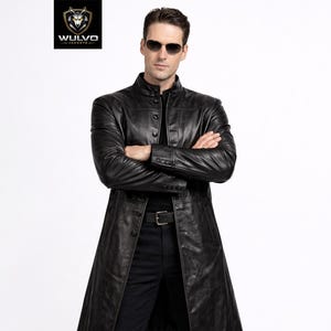 May include: A long, black leather trench coat with a button-up front, paired with black trousers and a belt. The coat's design is long and flowing. The image includes the "WULVO JACKETS" logo in the upper left corner.