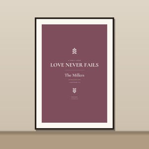May include: A framed wall art print featuring a deep plum background with white text that reads A FAMILY VERSE, LOVE NEVER FAILS, The Millers, ESTABLISHED 2023, and 1 CORINTHIANS 13:8. The design includes two small, stylized white leaf icons.