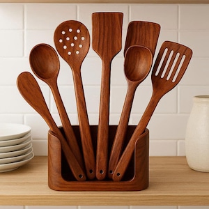 May include: A collection of seven wooden kitchen utensils, including spoons and spatulas, presented in a wooden holder. The utensils are a warm brown hue and have a smooth finish. The set is displayed on a light-coloured wooden shelf.