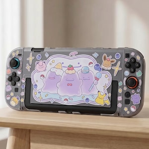 以下が含まれることがあります： 漫画のキャラクターが描かれた装飾ケース付きのグレーのNintendo Switchコンソール。ケースは紫と白のデザインで、さまざまなキャラクターのステッカーが付いています。コンソールは木製のテーブルの上にあります。