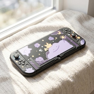 May include: A black handheld gaming console featuring a custom skin with a purple and yellow celestial theme. The design includes illustrations of smiling purple clouds, yellow stars, and a small yellow creature, extending across the controllers.